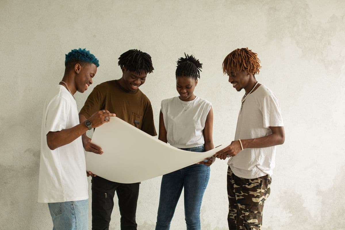 Four young adults reviewing a large sheet of paper together, smiling